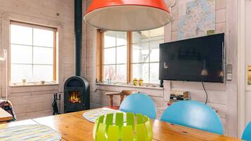 A room with a wooden table, chairs, a fireplace, a television, and a map on the wall.