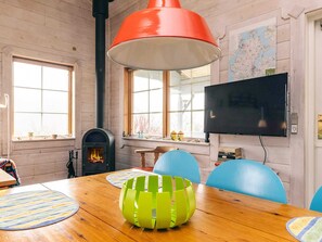 A room with a wooden table, chairs, a fireplace, a television, and a map on the wall. - 6 Person Holiday Home in Roslev (Roslev)