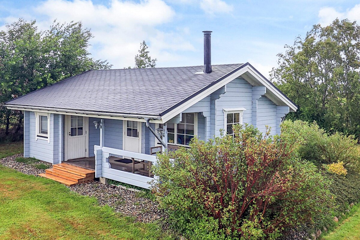 A single-story house with a gabled roof, a front porch, and a chimney.