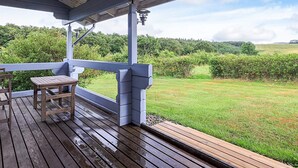 A covered outdoor area with a wooden deck, a table, and a bench. - 6 Person Holiday Home in Roslev (Roslev)