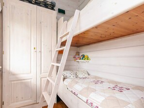 Una cama litera con escalera, una puerta de madera y un estante con juguetes de peluche.