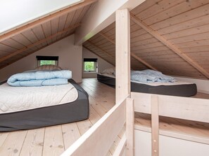 A loft bedroom with two beds, wooden beams, and a sloped ceiling. - 4 Star Holiday Home in Haderslev (Haderslev)