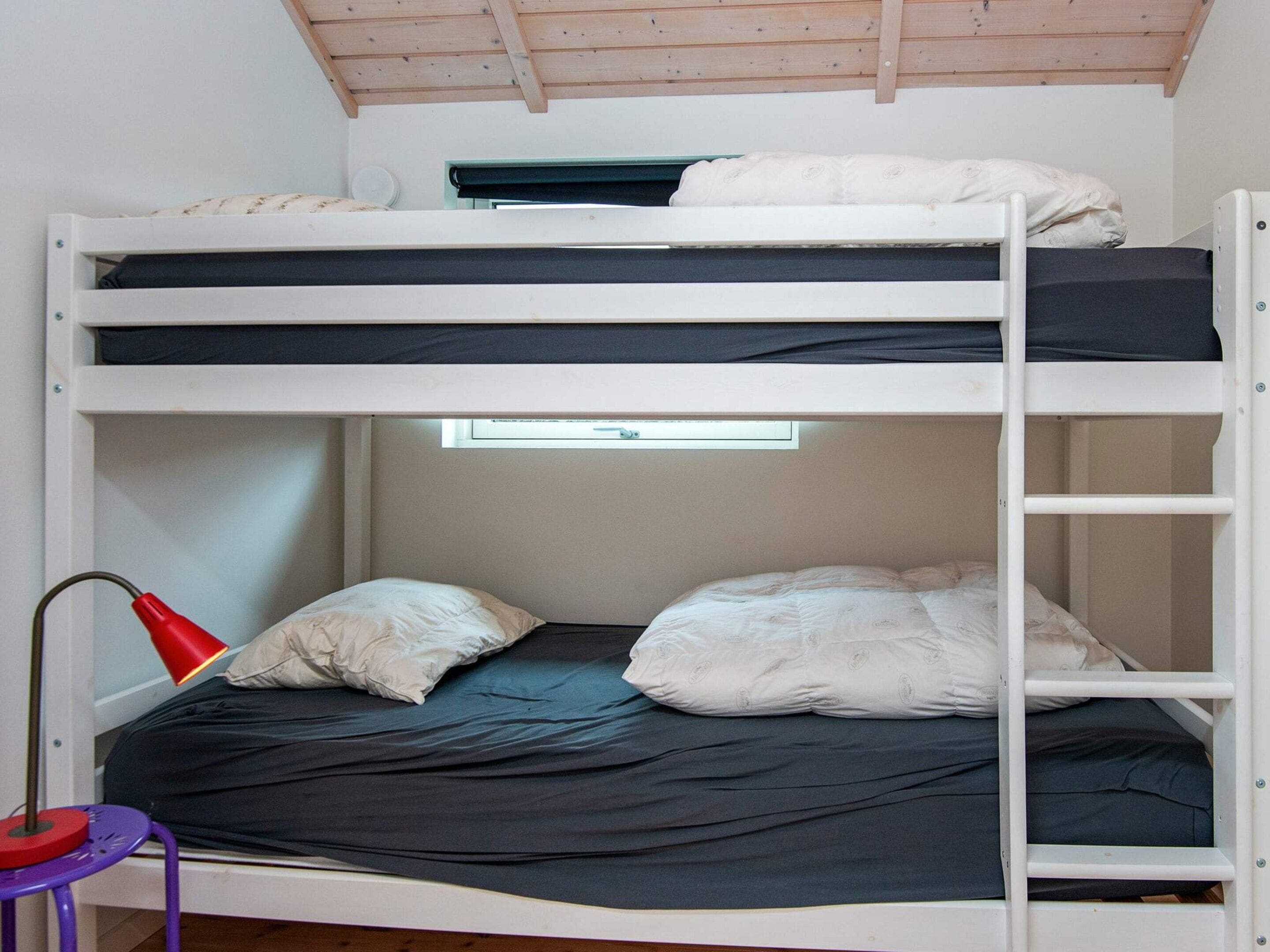 A bunk bed with a window above the lower bunk.