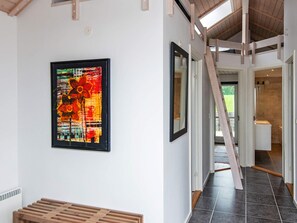 A hallway with a wooden bench, a framed abstract painting, and a staircase leading to another room. - 4 Star Holiday Home in Haderslev (Haderslev)