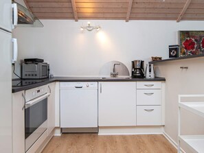 A compact kitchen with a microwave, toaster, coffee maker, and dishwasher. - 4 Star Holiday Home in Haderslev (Haderslev)