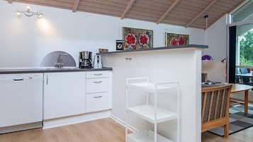 Una cocina moderna con armarios blancos, una cafetera y un comedor con mesa y sillas.