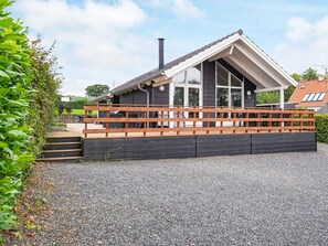 A modern house with a sloped roof, large windows, and a wooden deck. - 4 Star Holiday Home in Haderslev (Haderslev)
