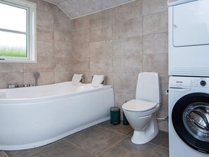 A modern bathroom with a freestanding bathtub, a toilet, and a washing machine.