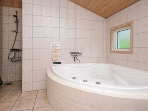 A bathroom with a large bathtub, a shower, and a window. - 5 Star Holiday Home in Oksbol (Oksbol)