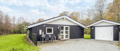 En tvåvåningsbyggnad med en grusuppfart, en täckt uteplats och ett garage.