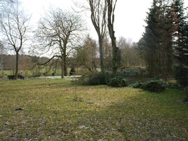 A park with a bench, trees, and a grassy area.