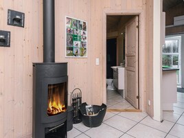 Una habitación con estufa de leña, pared de madera, un cartel y vistas hacia otra habitación.