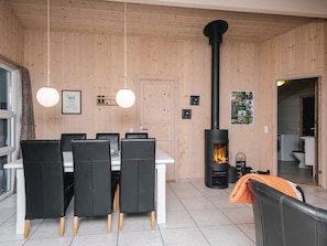 Un interno moderno con zona pranzo, parete rivestita in legno, camino e angolo lavanderia.