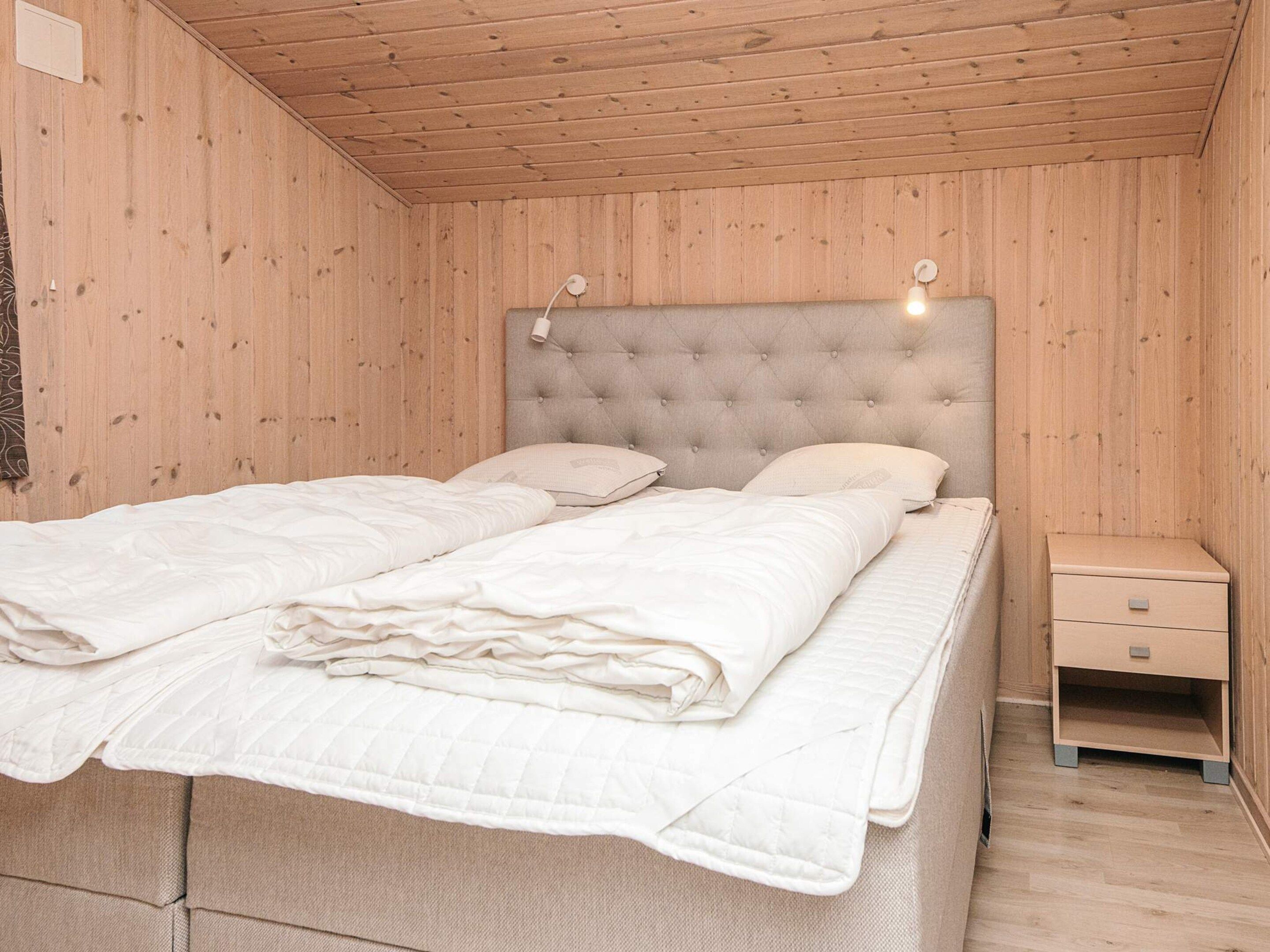 A double bed with a tufted headboard, two bedside tables, and a wooden floor.