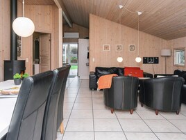 Un interior moderno con comedor, sofá de cuero negro y chimenea.