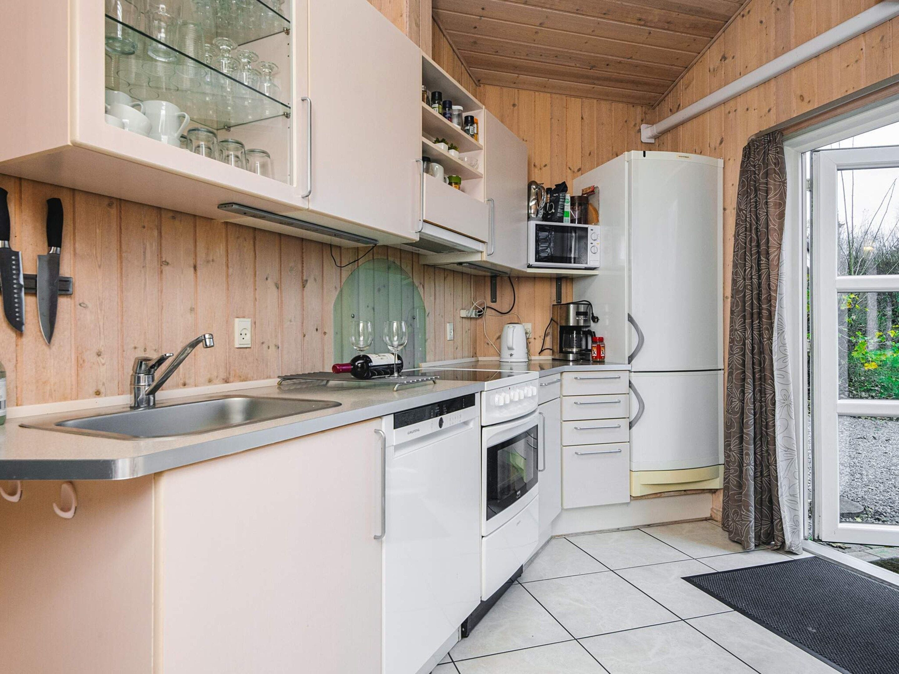 A compact kitchen with a sink, microwave, oven, and a refrigerator.