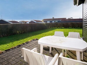 A patio with a white table and chairs, a paved area, and a hedge. - 4 Person Holiday Home in Hejls-by Traum (Hejls)