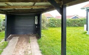 A covered outdoor area with a closed roller door, a concrete path, and a grassy lawn. - 4 Person Holiday Home in Hejls-by Traum (Hejls)