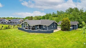 A row of modern, dark-colored cabins with a flat roof, surrounded by well-maintained grass lawns and trees. - 4 Star Holiday Home in Hemmet (Hemmet)
