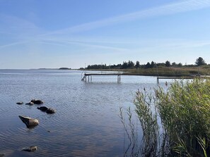 A calm lake with a dock extending into the water, surrounded by vegetation and a distant shoreline. - 4 Star Holiday Home in Hemmet (Hemmet)