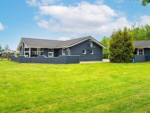 Il s’agit d’une propriété résidentielle dotée d’une cour clôturée et d’une maison avec un toit en pente et de nombreuses fenêtres.