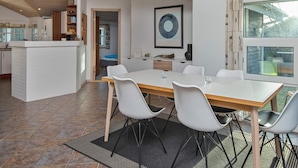 A modern kitchen with white cabinetry, a dining area with a large table and chairs, and a view of the outdoors through a large window. - 4 Star Holiday Home in Hemmet (Hemmet)