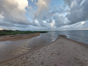 A beach with a curved shoreline, a sandy foreground, and a distant view of a body of water under a cloudy sky. - 4 Star Holiday Home in Hemmet (Hemmet)
