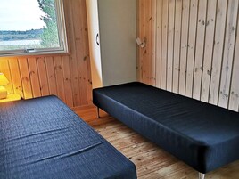 A room with two beds, wooden walls, and a window with a view.