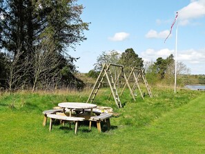 A picnic area with a wooden table and benches, surrounded by trees and a flagpole. - Spacious Holiday Home in Højslev near Sea (Hojslev)
