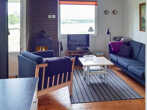A living room with a fireplace, a sofa, a television, and a table.