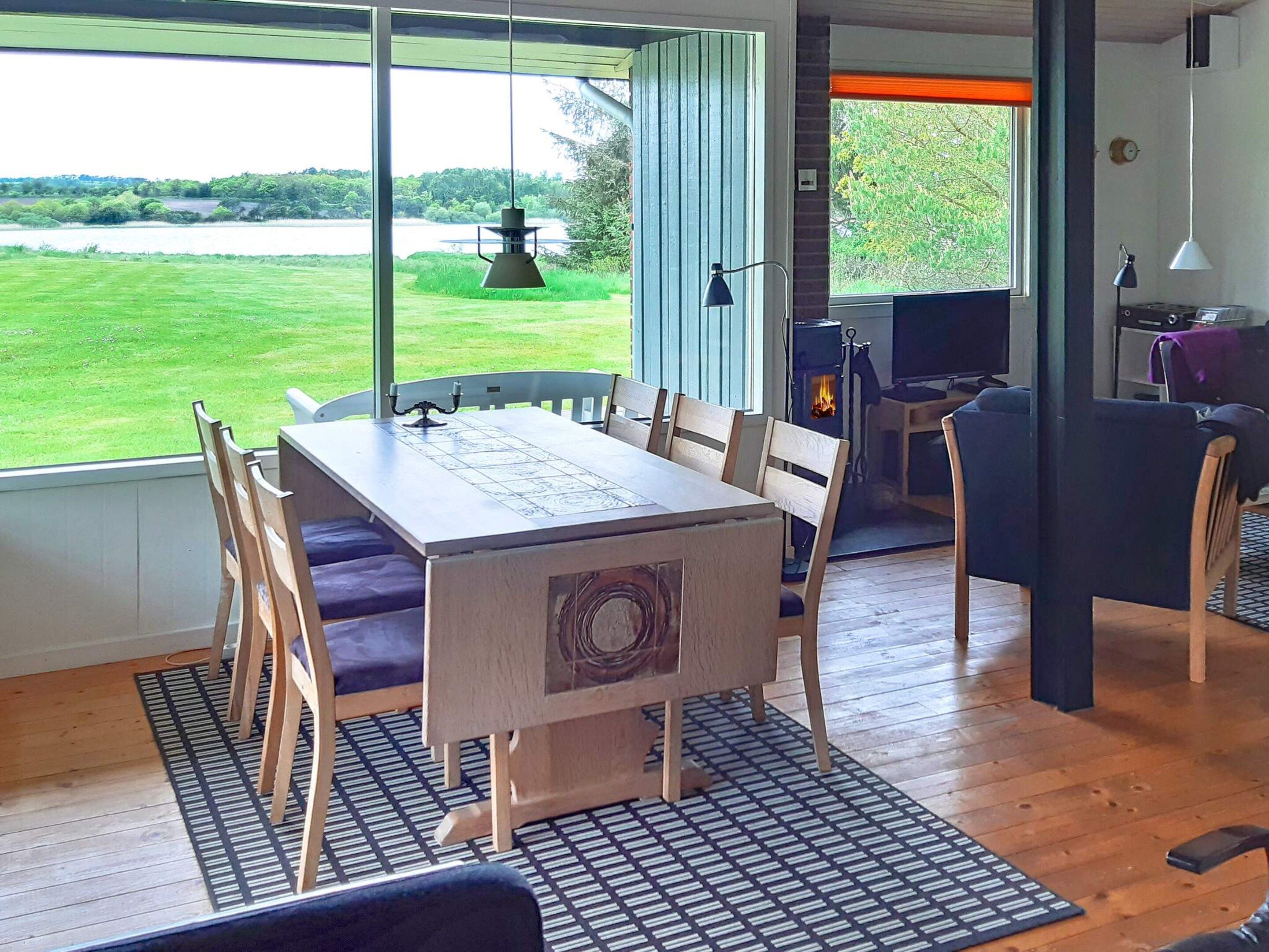 A dining area with a table and chairs, a view of a lake, and a wood-burning stove.