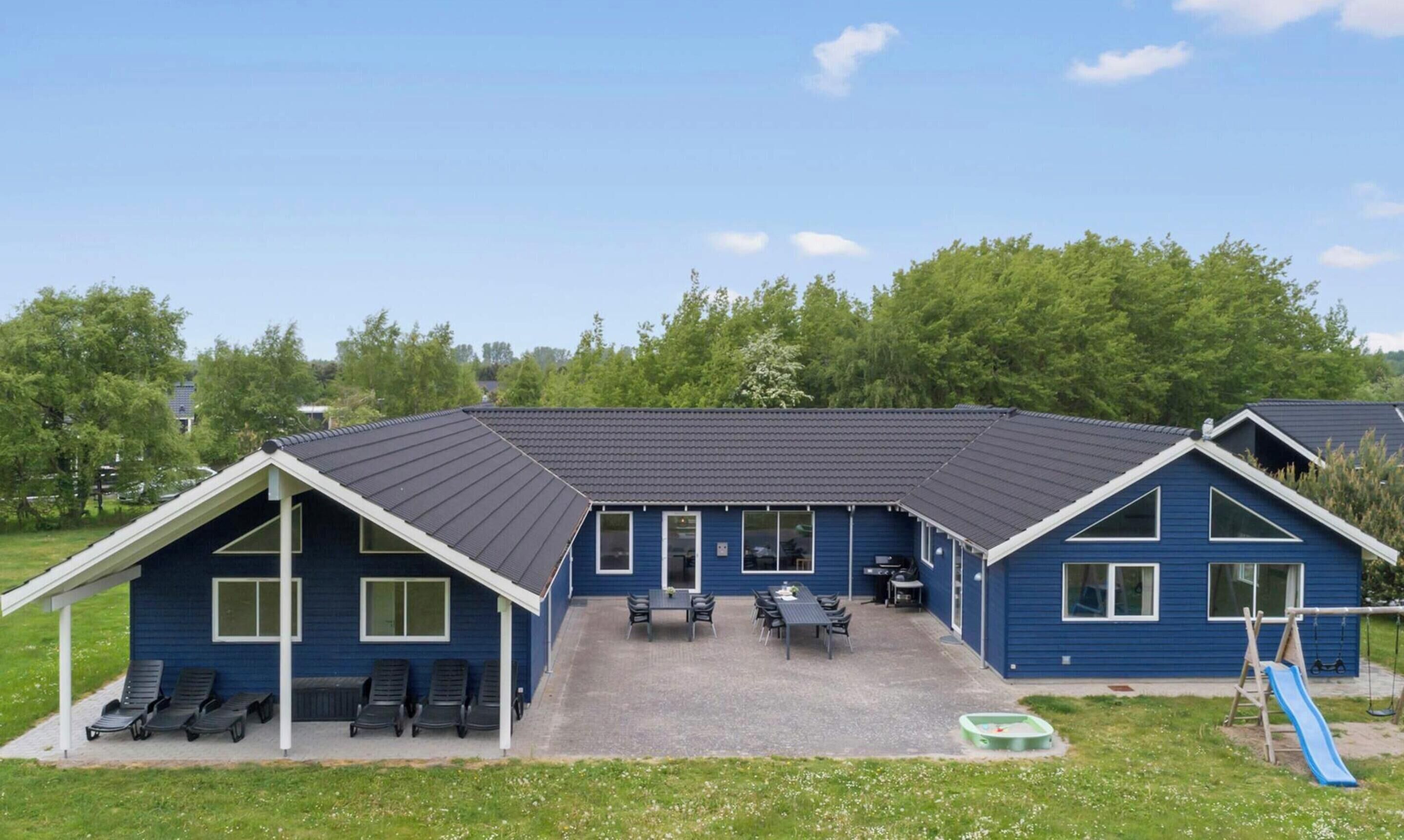 A blue building with a covered patio, outdoor seating, and a children's play area.