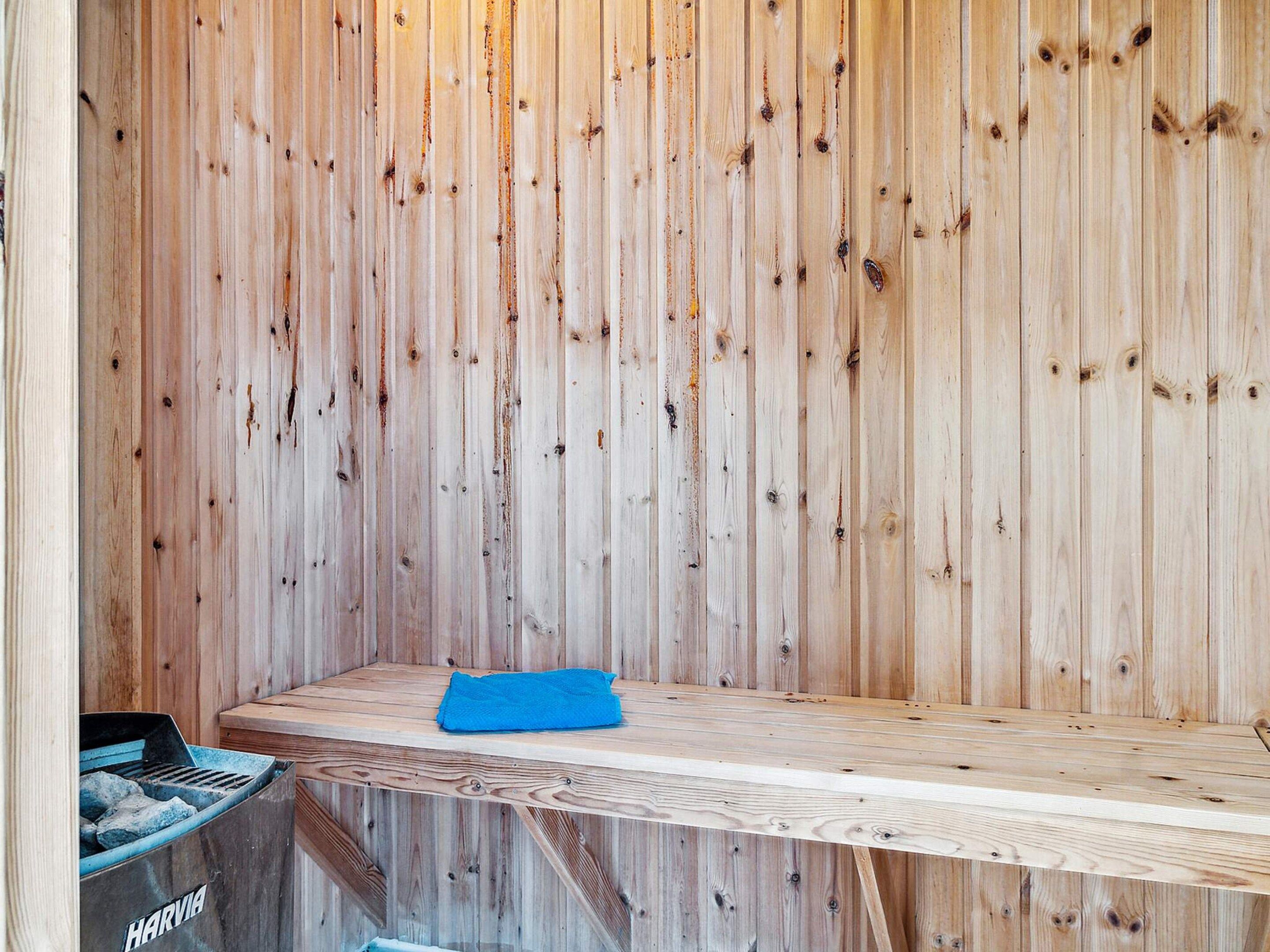 Ein Saunaraum mit einer Holzbank und einem blauen Handtuch.