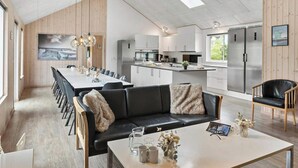 Een moderne keuken met witte kastjes, een roestvrijstalen koelkast en een eethoek met een lange tafel en stoelen.