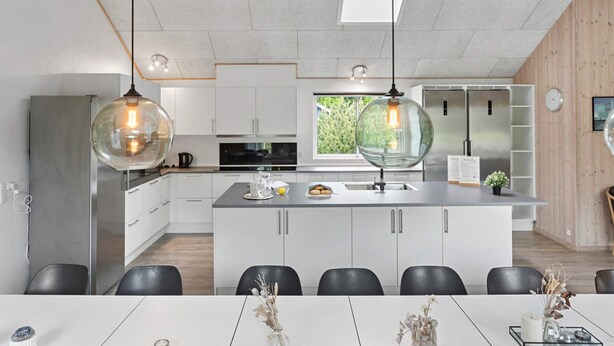 Een moderne keuken met witte kasten, een centraal eiland en hanglampen.
