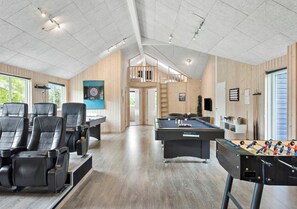 Uma área de lazer moderna, com mesa de bilhar, mesa de pebolim e poltronas reclináveis.