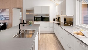 Een moderne keuken met roestvrijstalen apparatuur, witte keukenkastjes en een wand met houten accenten.