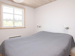 Una habitación con cama, ventana y dos lámparas de pared.