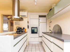 A compact kitchen with white cabinets, a stainless steel range hood, a built-in oven, and a sink.