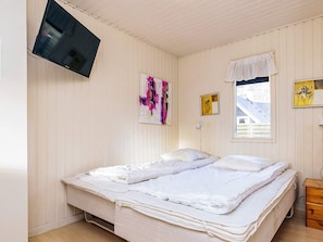 A bedroom with two beds, a TV mounted on the wall, and artwork on the walls.