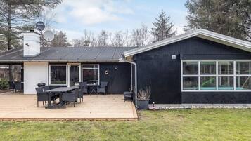 A modern house with a deck, a covered patio, and a large window.