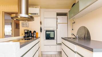 A compact kitchen with a built-in oven, a stainless steel range hood, and a sink with a modern faucet.