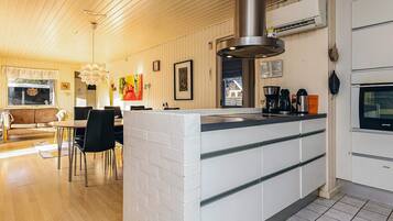 A modern kitchen with a central island, white cabinetry, and a stainless steel range hood.