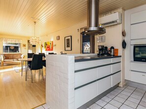 A modern kitchen with a central island, white cabinetry, and a stainless steel range hood. - 8 Person Holiday Home in Hals (Hals)
