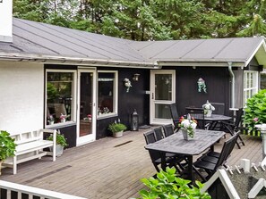 A covered outdoor patio with a table and chairs, a white bench, and potted plants. - 8 Person Holiday Home in Hals (Hals)