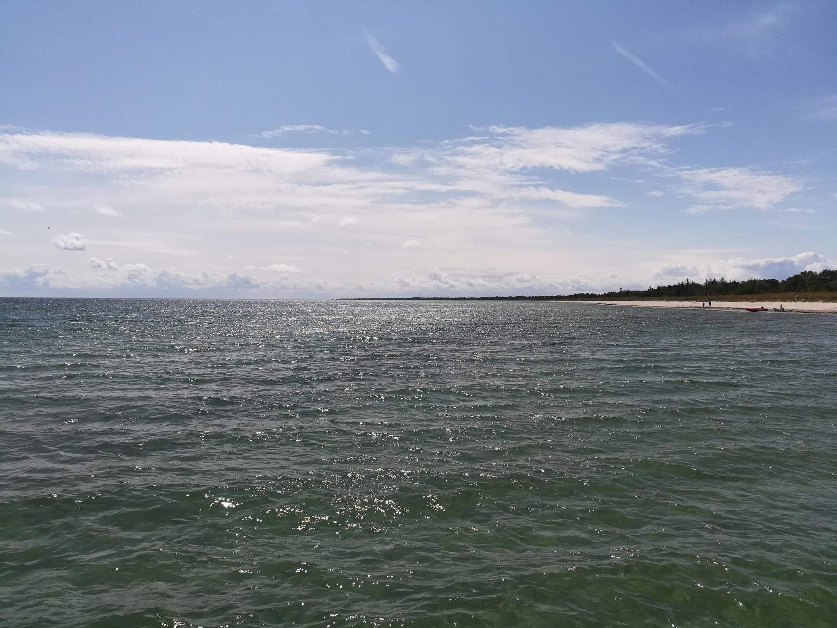 A beach with calm waters and a clear sky.