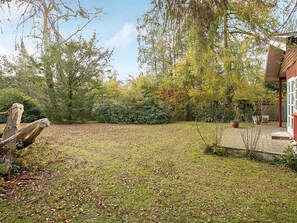A garden with a wooden fence, a small shed, and a variety of trees.