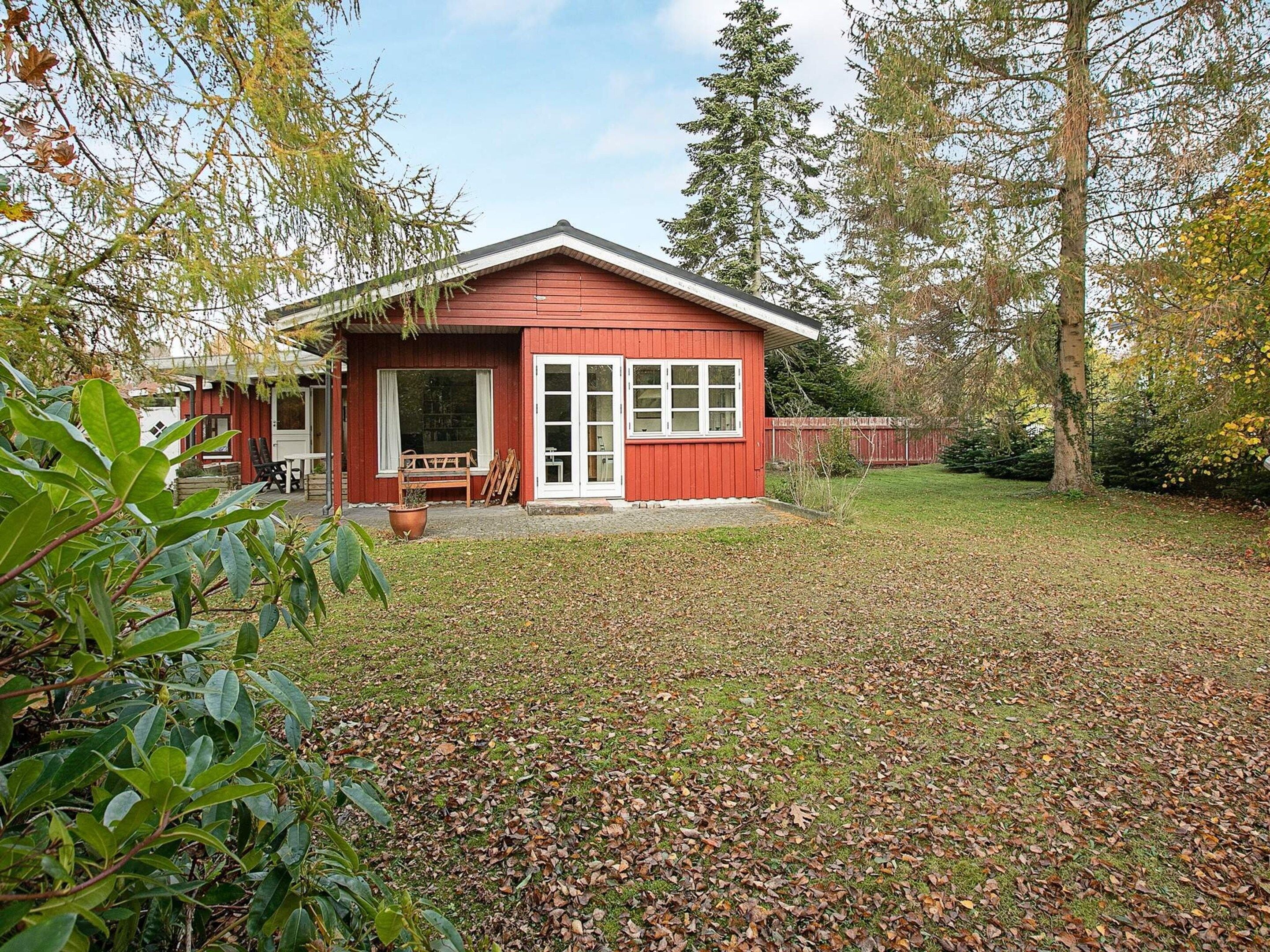 Eine rote Holzhütte mit Veranda, einer Bank und einem Blumentopf.