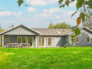A two-story house with a covered patio and a lawn. - 5 Star Holiday Home in Grenaa (Grenaa)