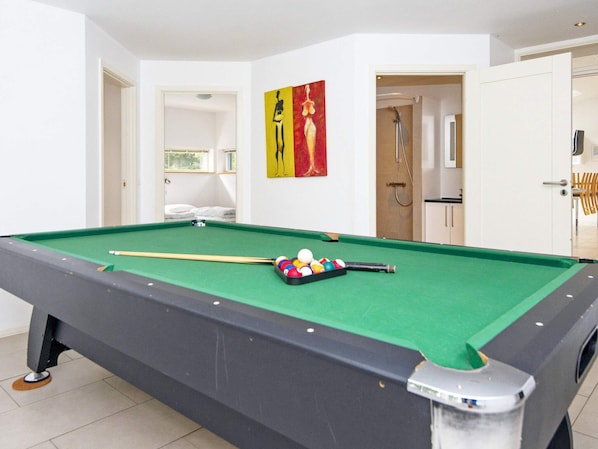 A pool table with balls and a cue stick, a door leading to a bathroom, and a painting on the wall. - 5 Star Holiday Home in Grenaa (Grenaa)